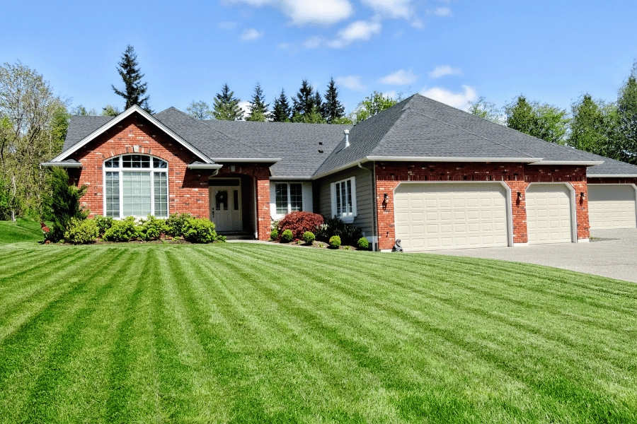 Brick ranch style home with multiple garages and large freshly mowed front lawn